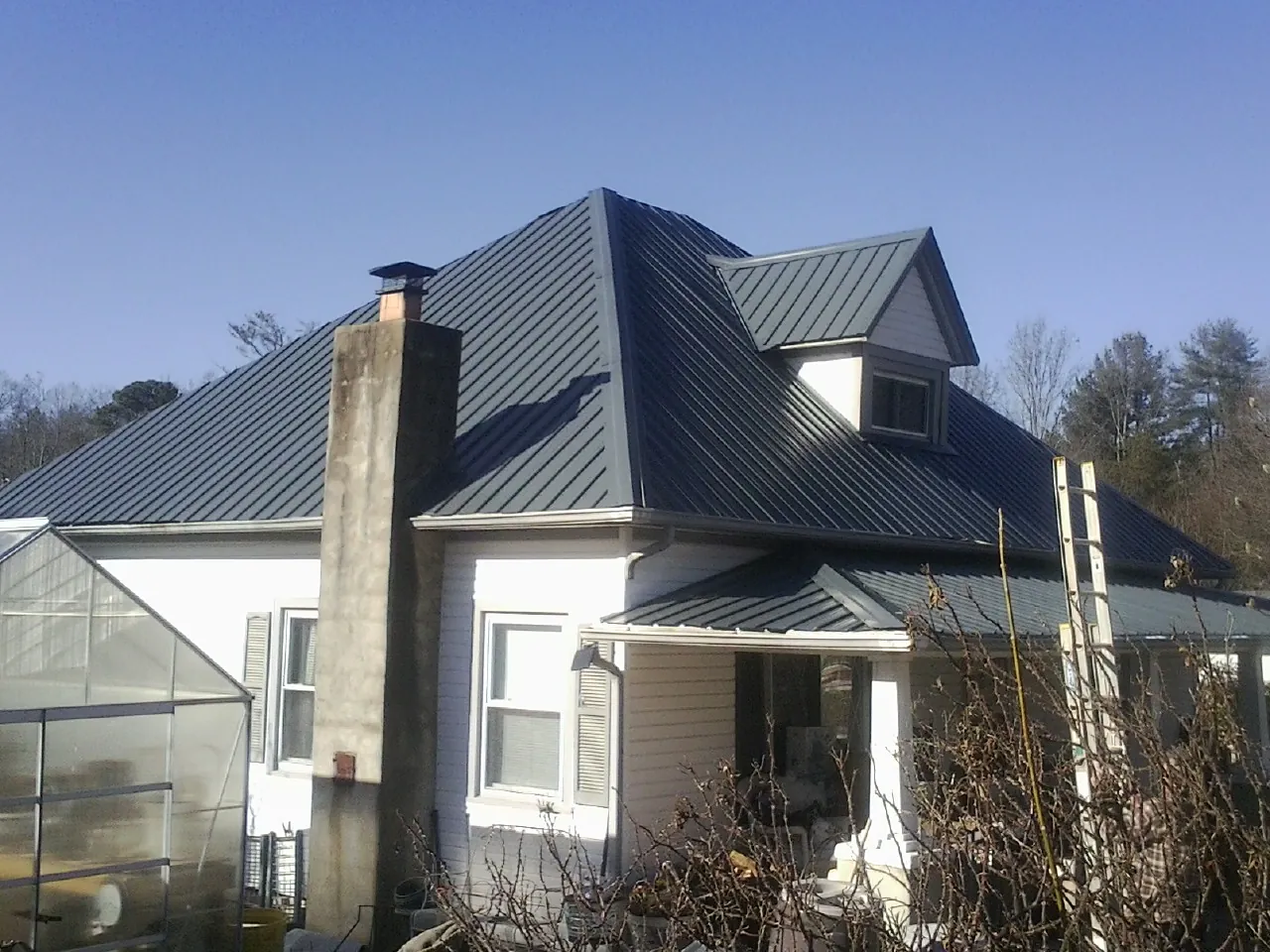 Dark blue standing seam metal roof on a white farmhouse with dormer — Slate & Tile Roof Repair by Roofing Brothers in Bremen