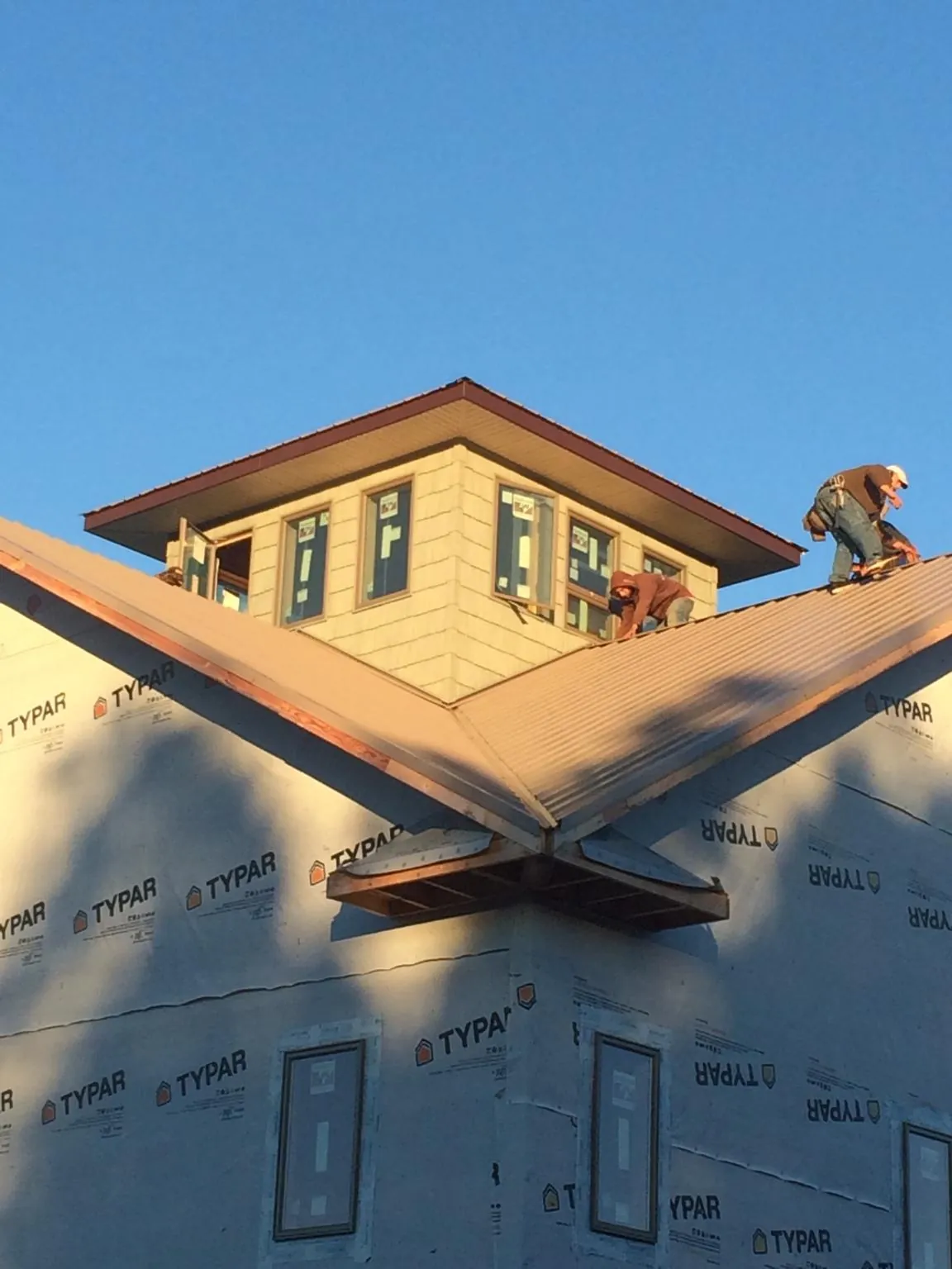 Roofers working around a rooftop cupola on a new metal roof at sunset — Roof Waterproofing in Bremen by Roofing Brothers